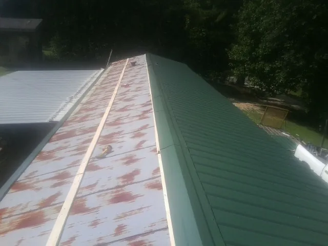 Old rusted panels beside newly installed green metal roofing — Wind Damage Roof Repair by Roofing Brothers in Darien