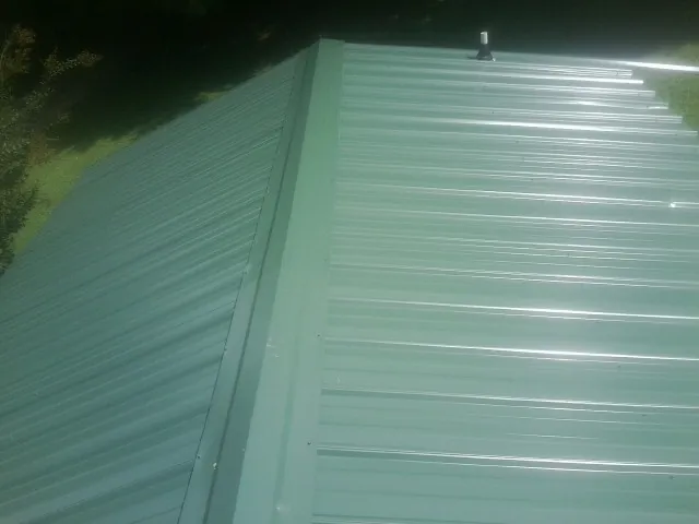 New green metal panels meeting at the ridge of a roof — Flat Roof Repair work by our crew in Darien