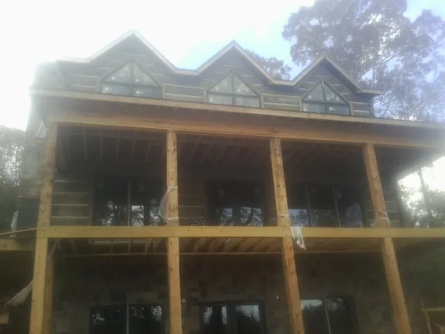 Dormers and porch framing on a large log home under construction — Roof Coating work by our crew in Darien
