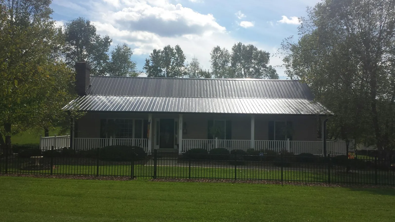 Gray metal roof on a brick ranch with a full width front porch — Gutter Guard Installation work by our crew in Darien