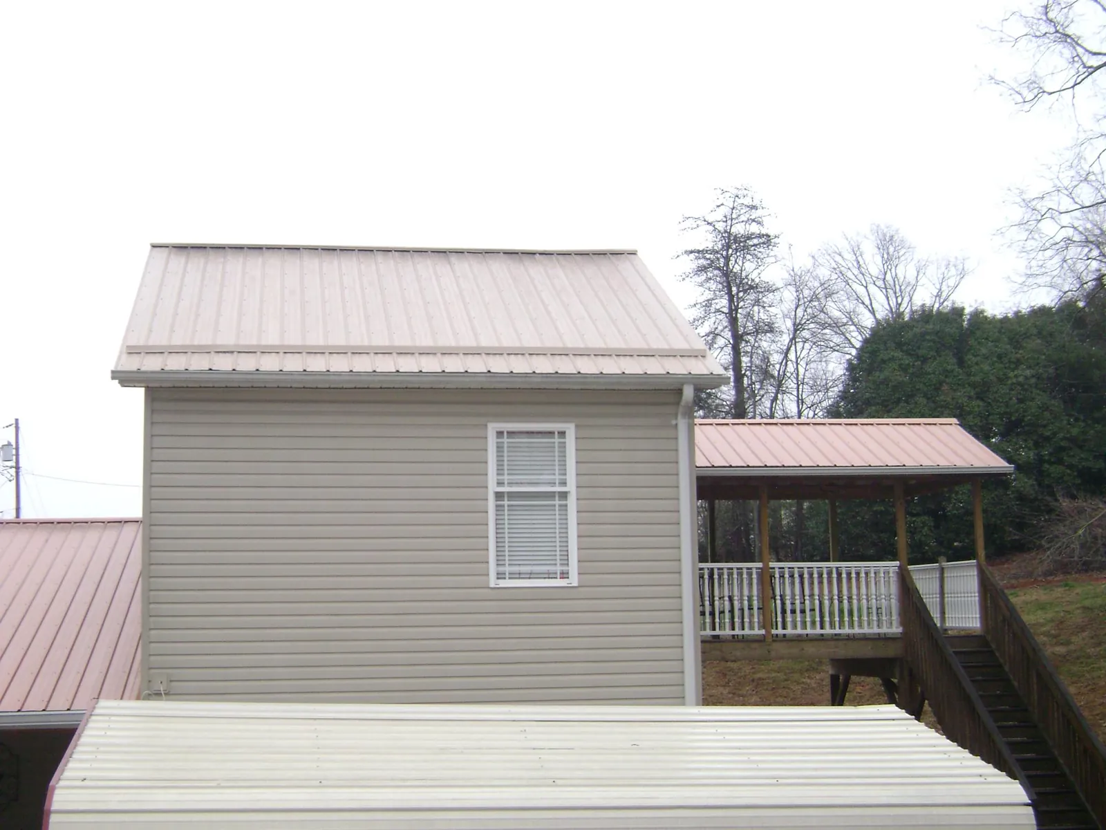 Tan metal roofs on a two story addition and attached porch, from a Roof Replacement job in Darien