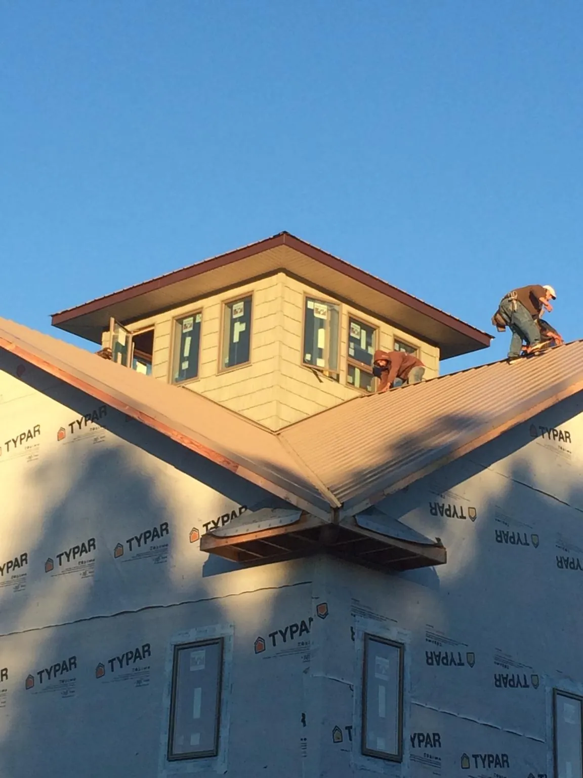 Roofers working around a rooftop cupola on a new metal roof at sunset — Roof Waterproofing in Darien by Roofing Brothers